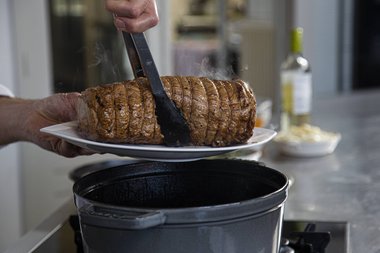 Kalfsvlees uit de braadpan halen.
